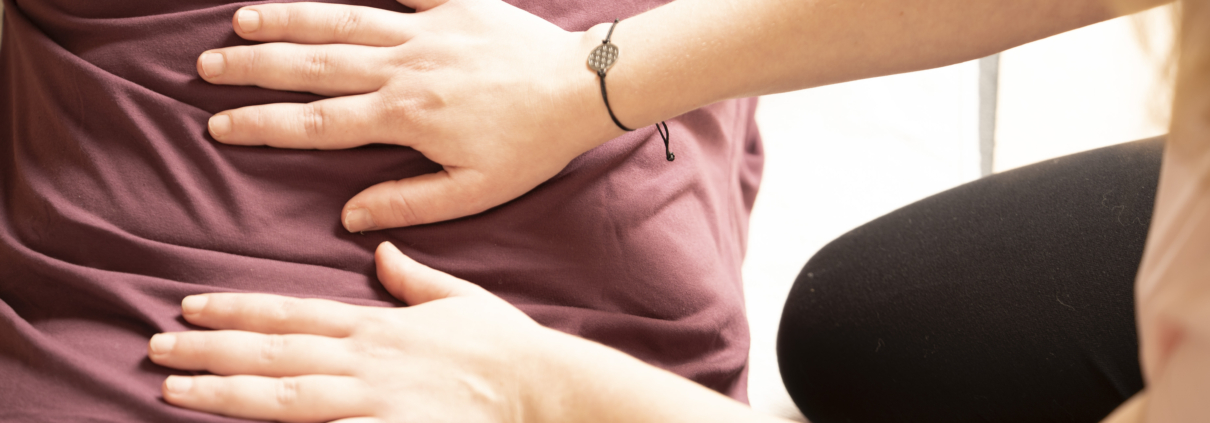 Claudia Sontheimer fühlt mit Händen Rückenverspannungen im unteren Rücken