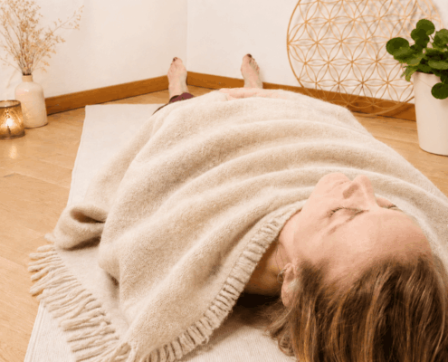 Claudia zugedeckt in beiger Wolldecke in Shavasana