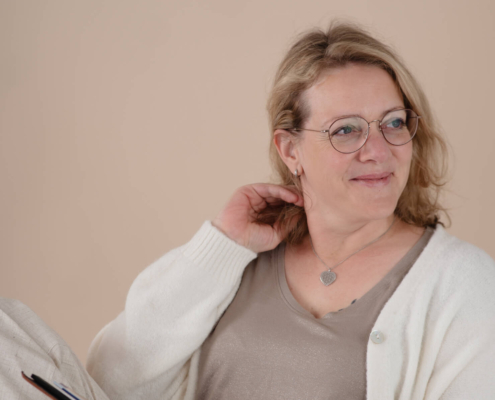 Claudia Sontheimer hält ihr Praxis-Notizbuch in der Hand und blickt nachdenklich zur Seite – Symbolbild für die Analyse von Befunden im Therapiegespräch.