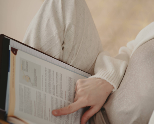 Nahaufnahme einer Hand, die in einem Fachbuch zur Frauengesundheit eine Textstelle nachschlägt.