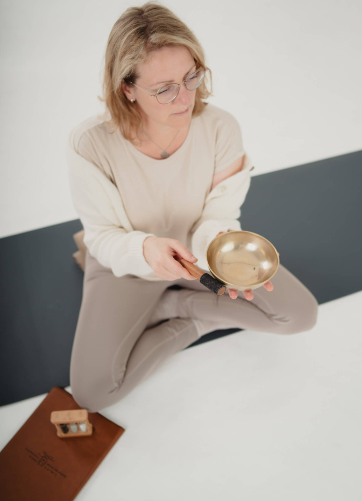 Claudia mit Klangschale auf der Yoga-Matte