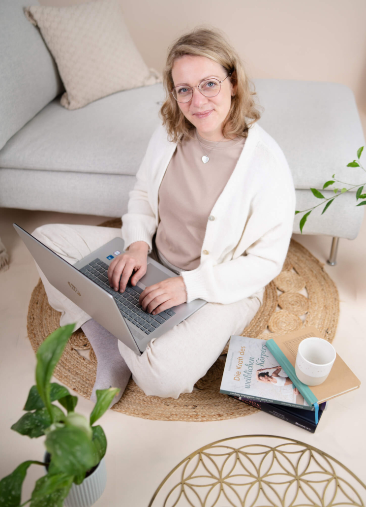 Claudia sitzt am Boden und schreibt am Laptop