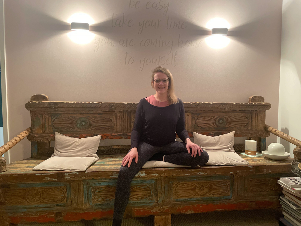 Claudia sitzend auf der Holzbank nach bestandener 300h Yoga-Lehrer Ausbildung 
